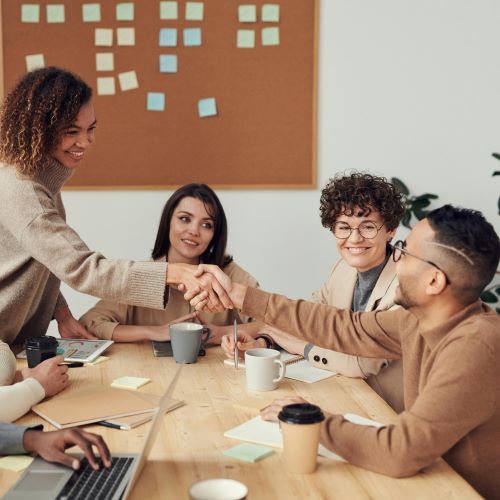 a diverse group of professionals engaged in a collaborative discussion around a table in a bright, modern workspace.